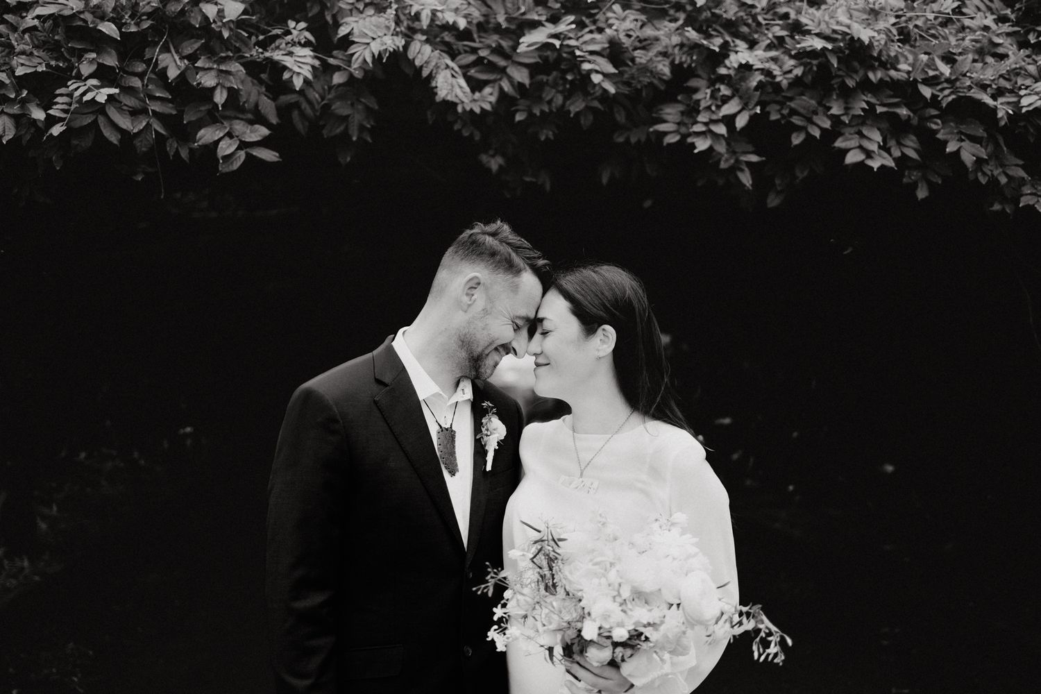 Black and white wedding portrait of newlyweds sharing an intimate moment, captured by Apertured Media Auckland Wedding Photographer.