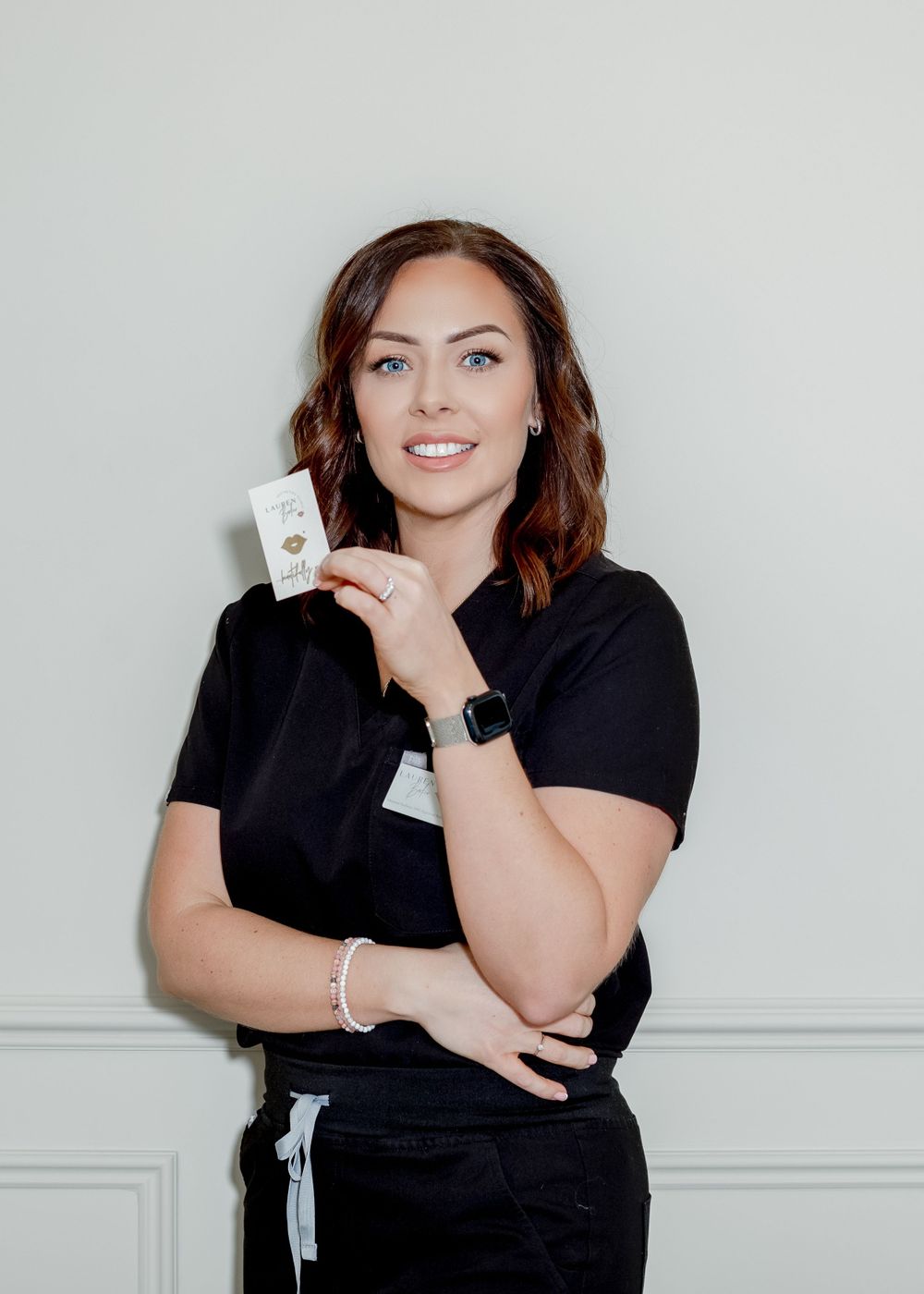 Medical professional in black uniform showing product while wearing smartwatch and bracelet.