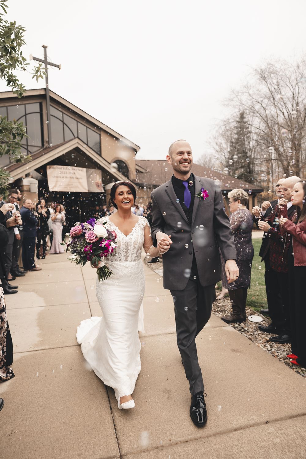 Beaming newlyweds step into forever surrounded by cheers, laughter and bubbles at Church of the Holy Angels in Chagrin Falls, Ohio.