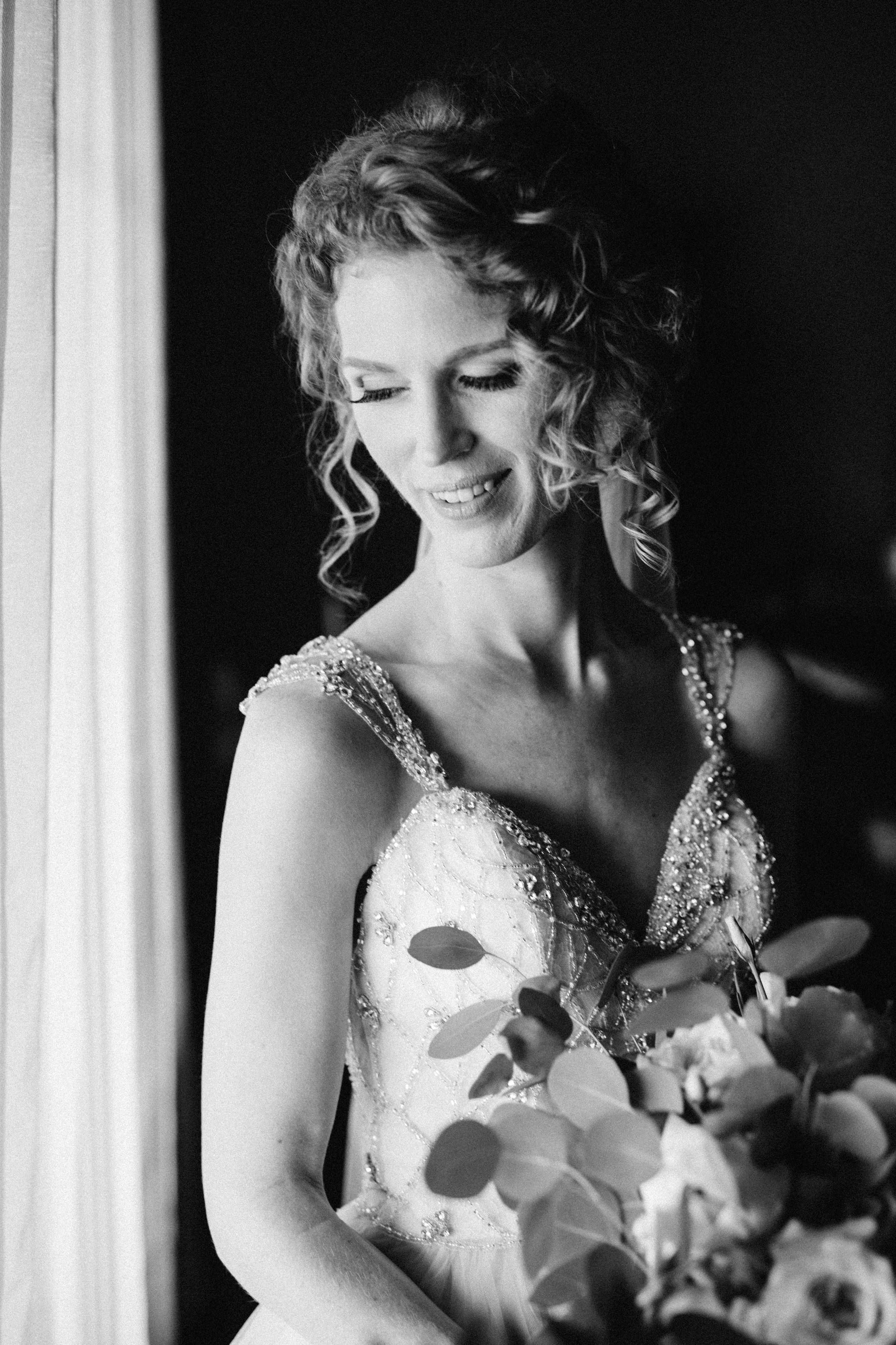 Black and white portrait showcasing an elegant bridal look with curled hair and decorative dress.