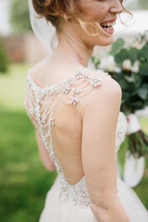 Close-up of an intricate beaded back detail on a wedding dress with floral embellishments.