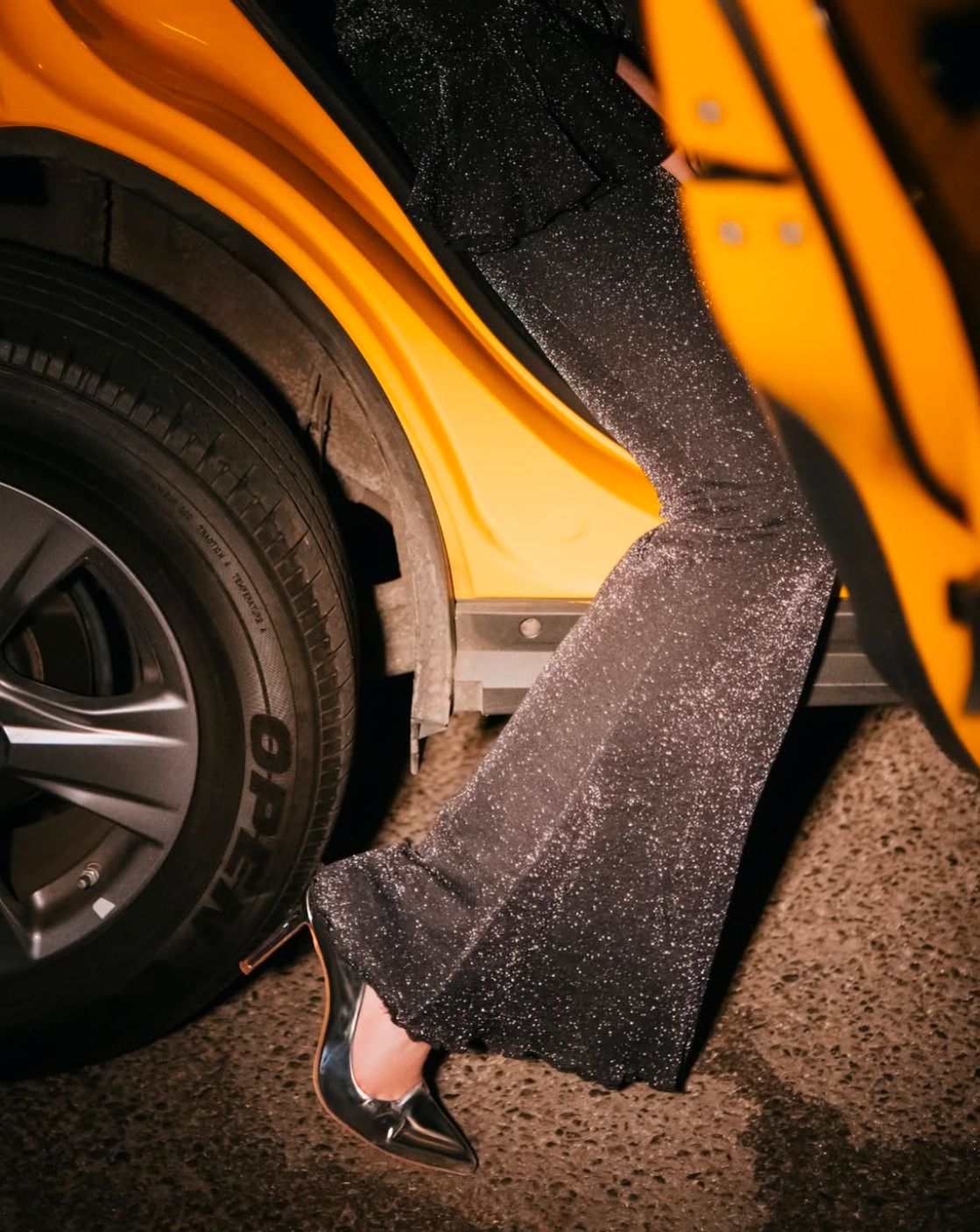 Black boots and yellow car wheel in dramatic lighting.
