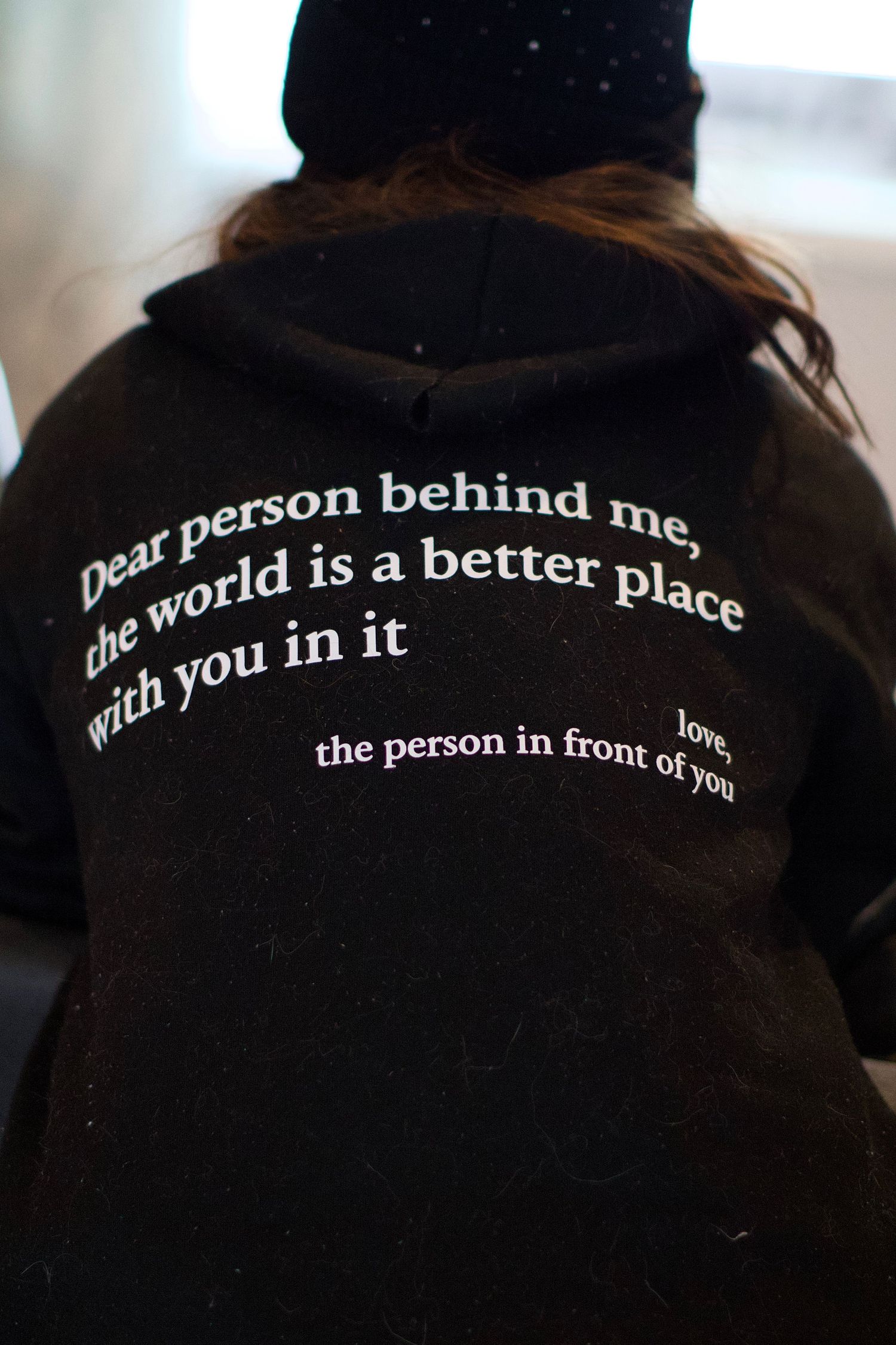 Black hoodie with inspirational message about making the world better written on back.