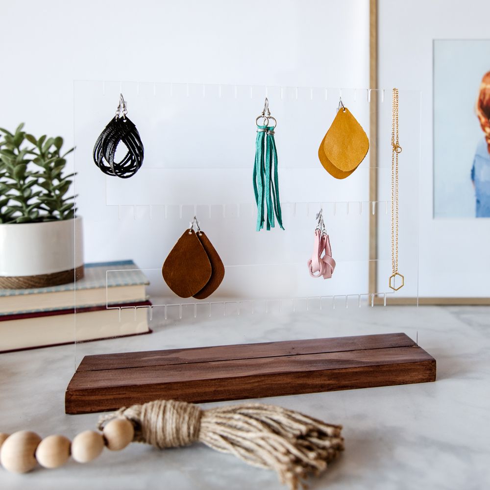 Decorative hanging tassels and beaded accessories displayed on wooden shelf with potted plant.