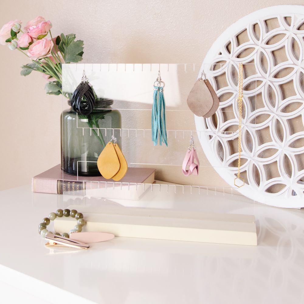 Pink shelf with decorative tassels, vase of roses, and white geometric wall art.