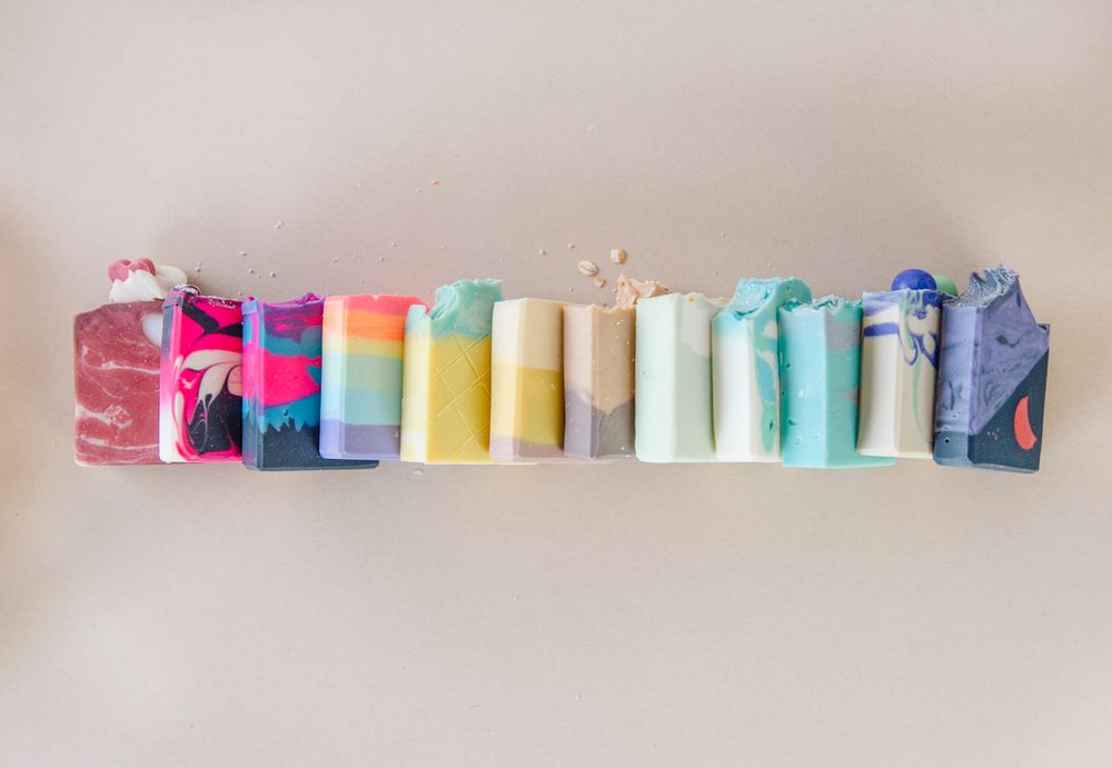 Collection of pastel colored soap bars arranged in ombre pattern on wall.