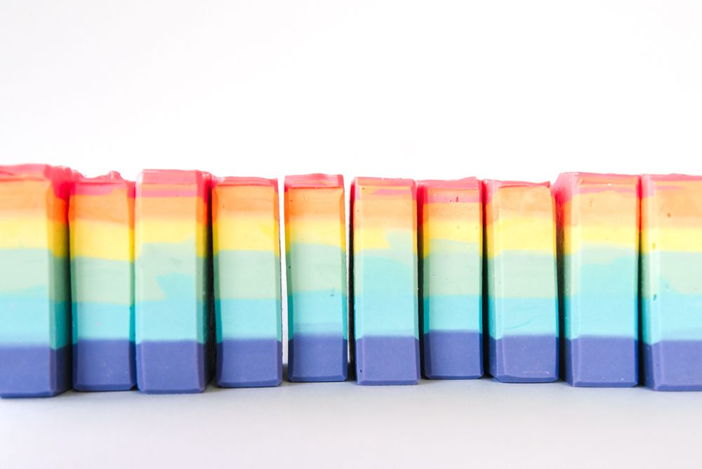 Rainbow colored soap bars lined up in uniform rows showing vibrant gradient pattern.