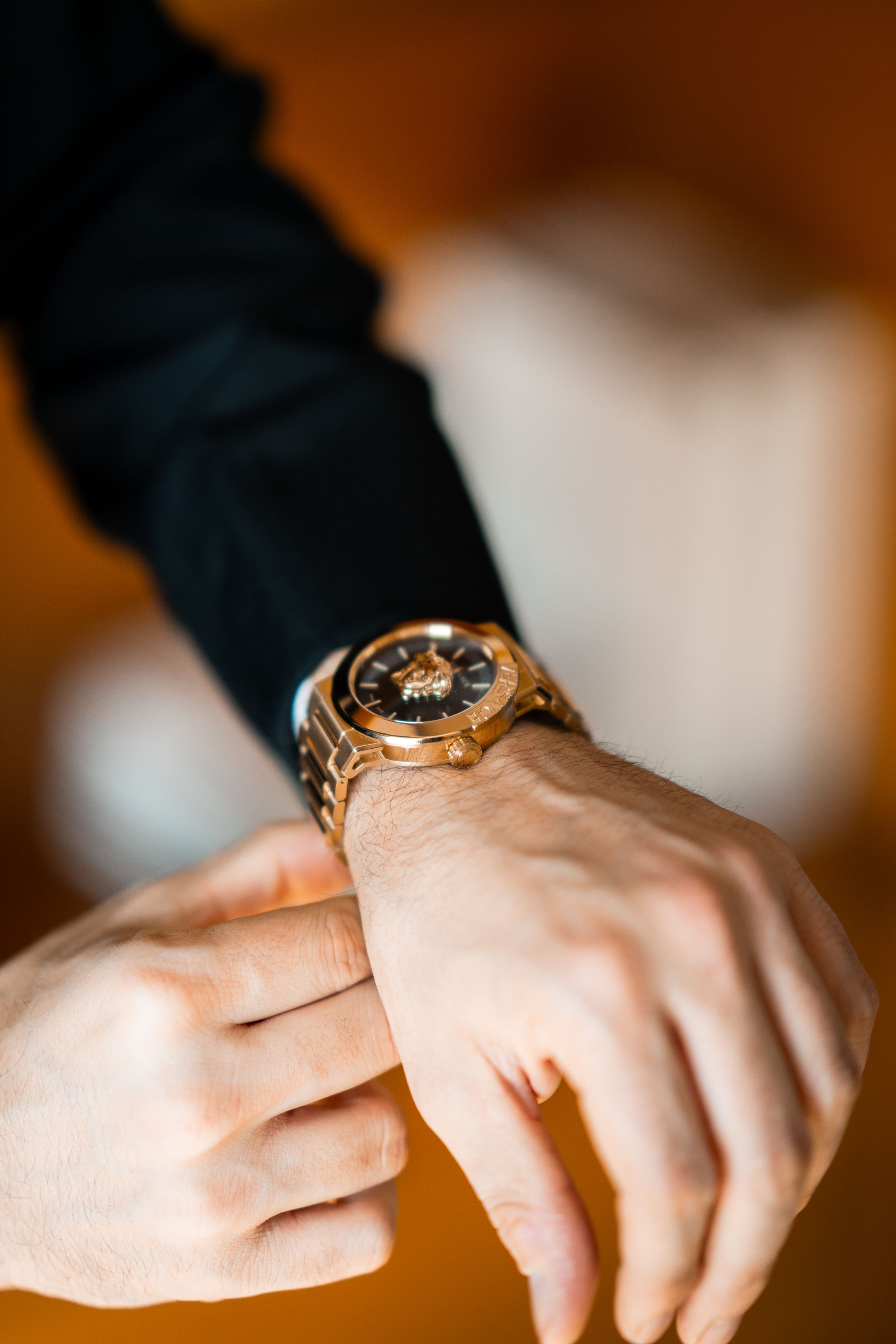 Detail shot of an elegant gold watch on wrist with formal wear.