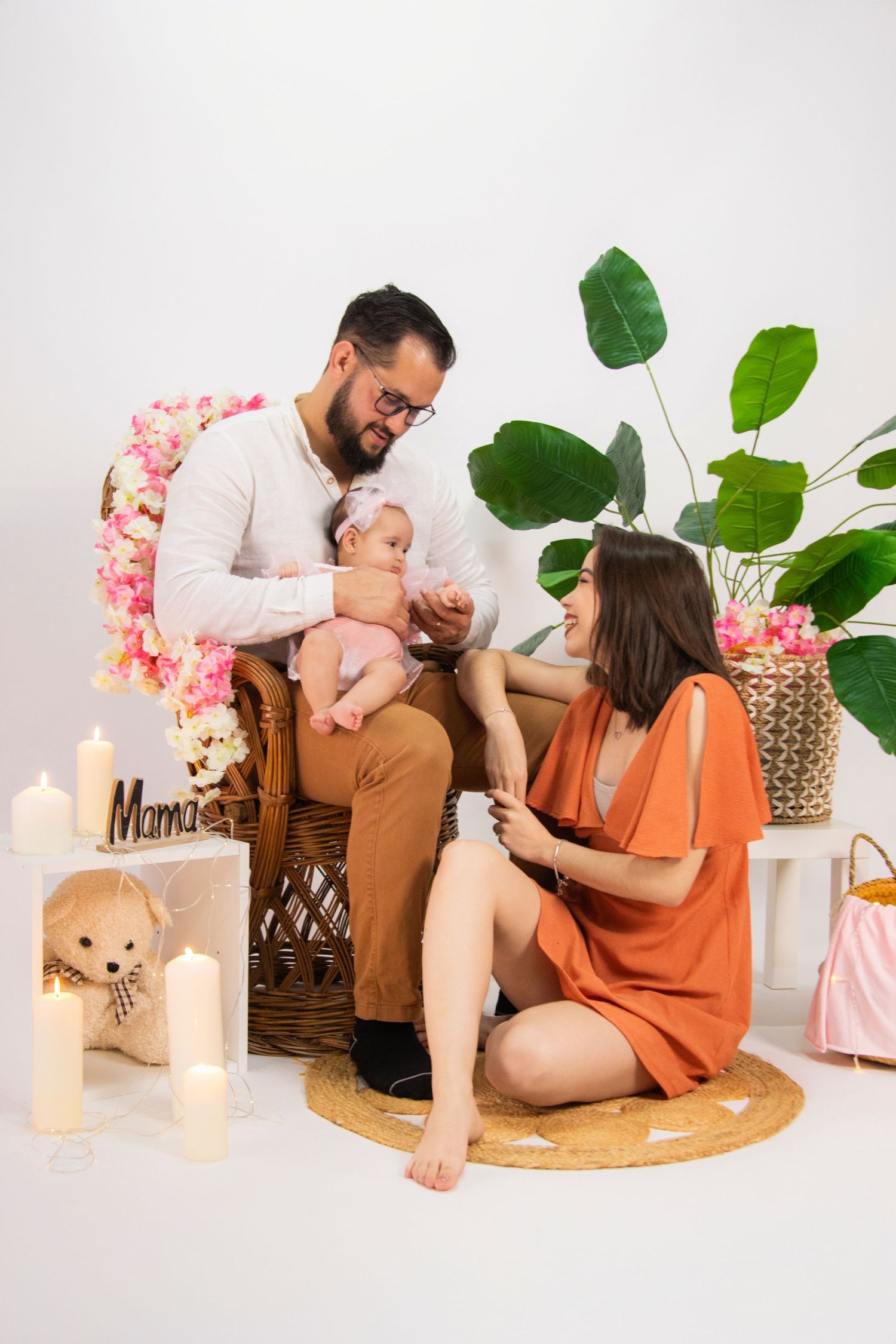 Family relaxing together on round wooden platform with candles and plants.