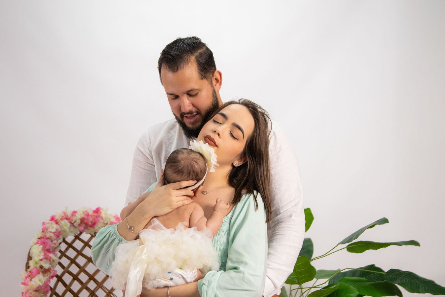 Tender family moment photographed in bright studio setting with plants.