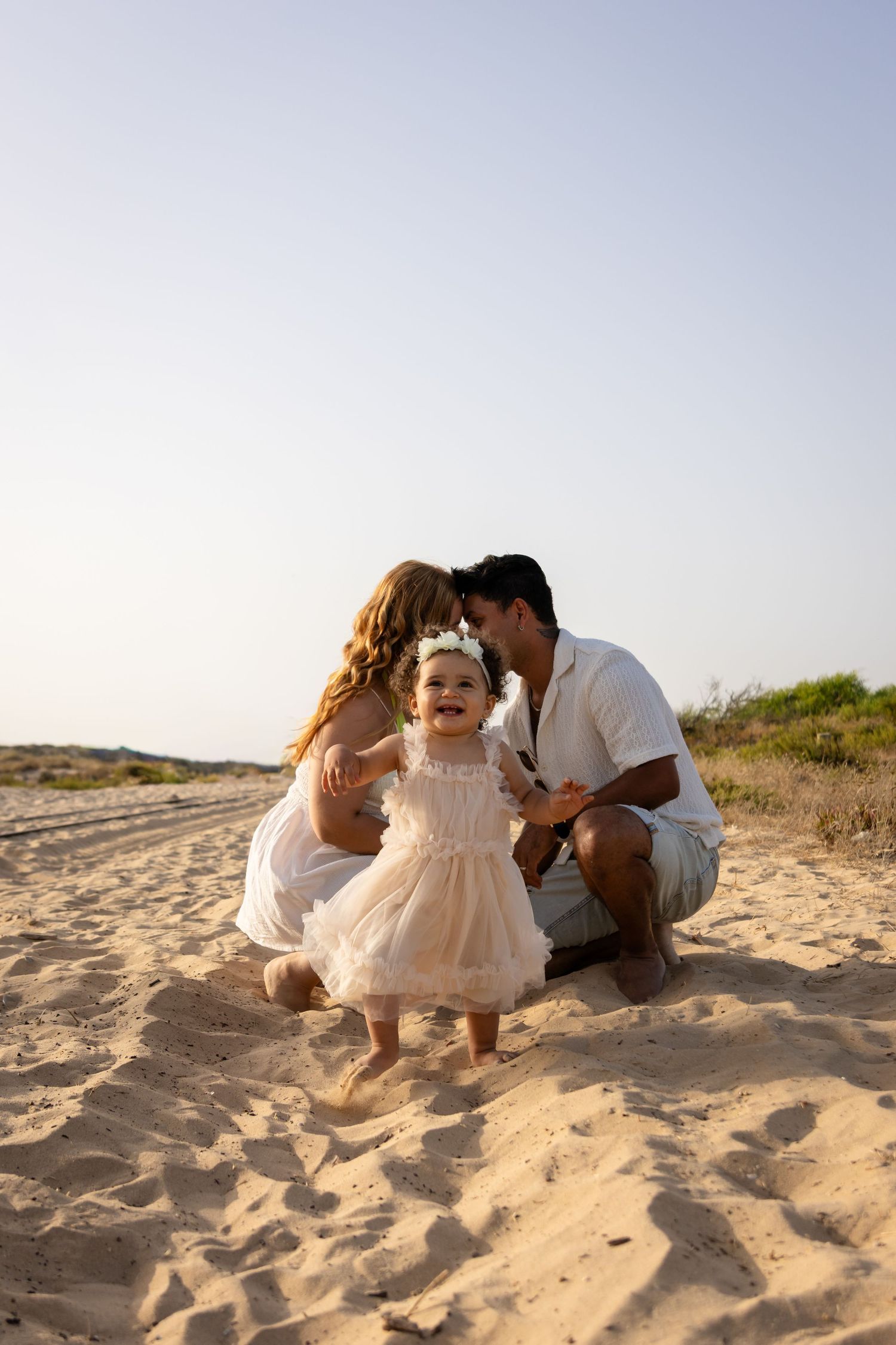 Family playing together on sandy beach during outdoor photo session.