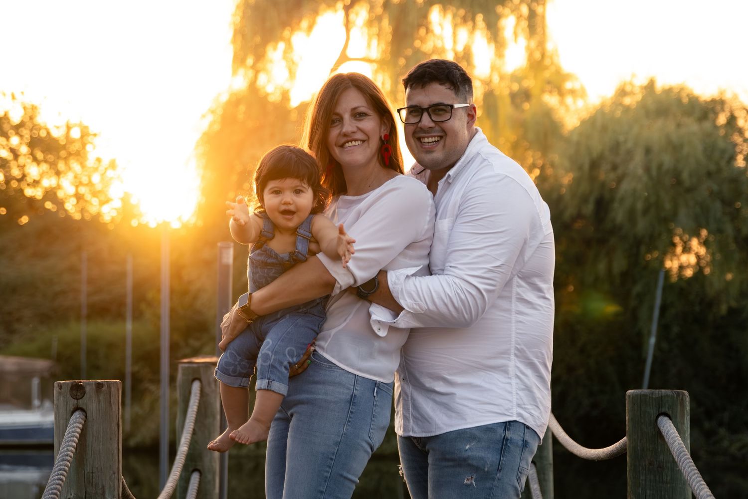 Family portrait at sunset with golden light streaming through trees in background.
