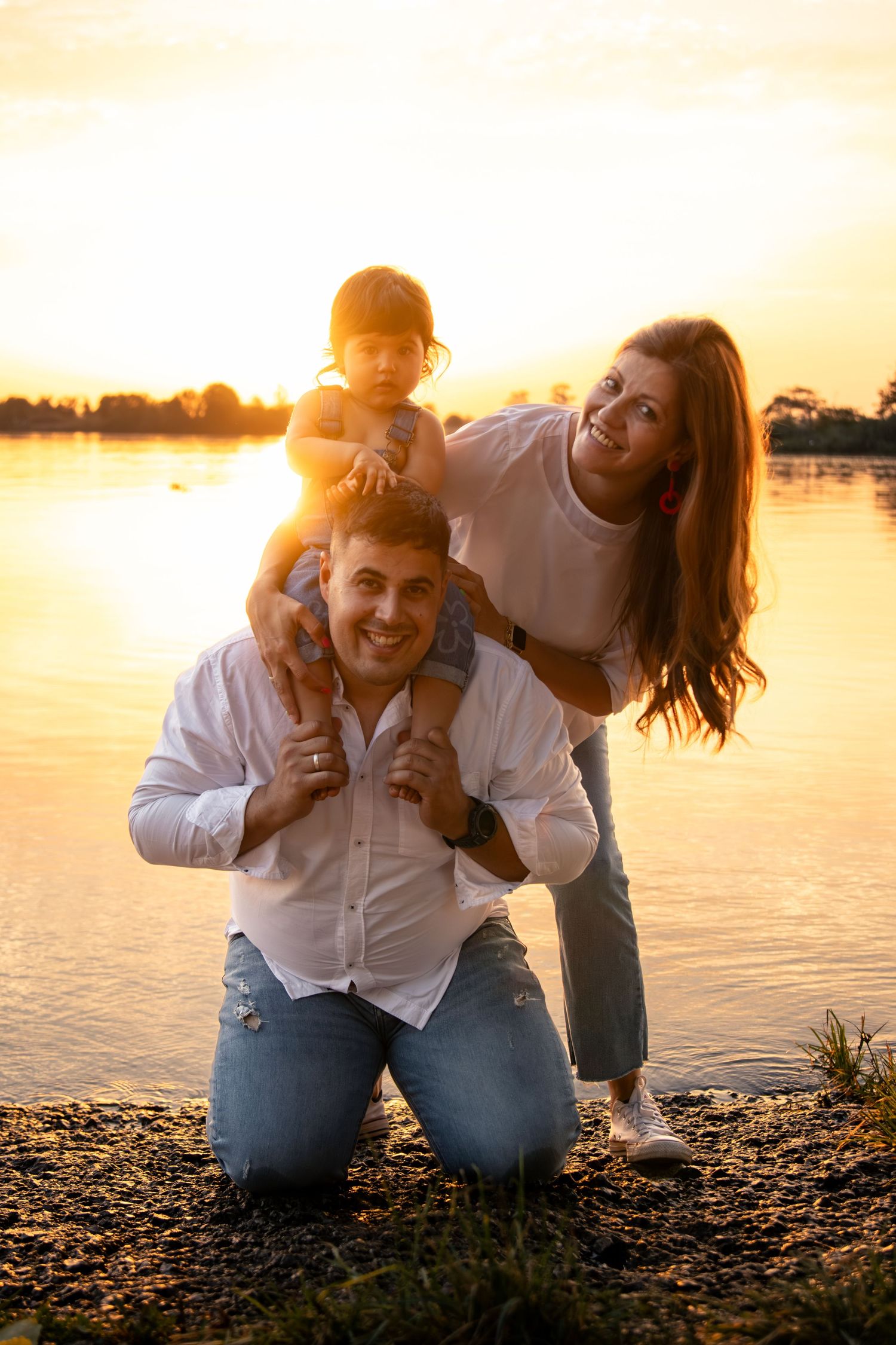 Playful family enjoying a sunset photoshoot by the water's edge.