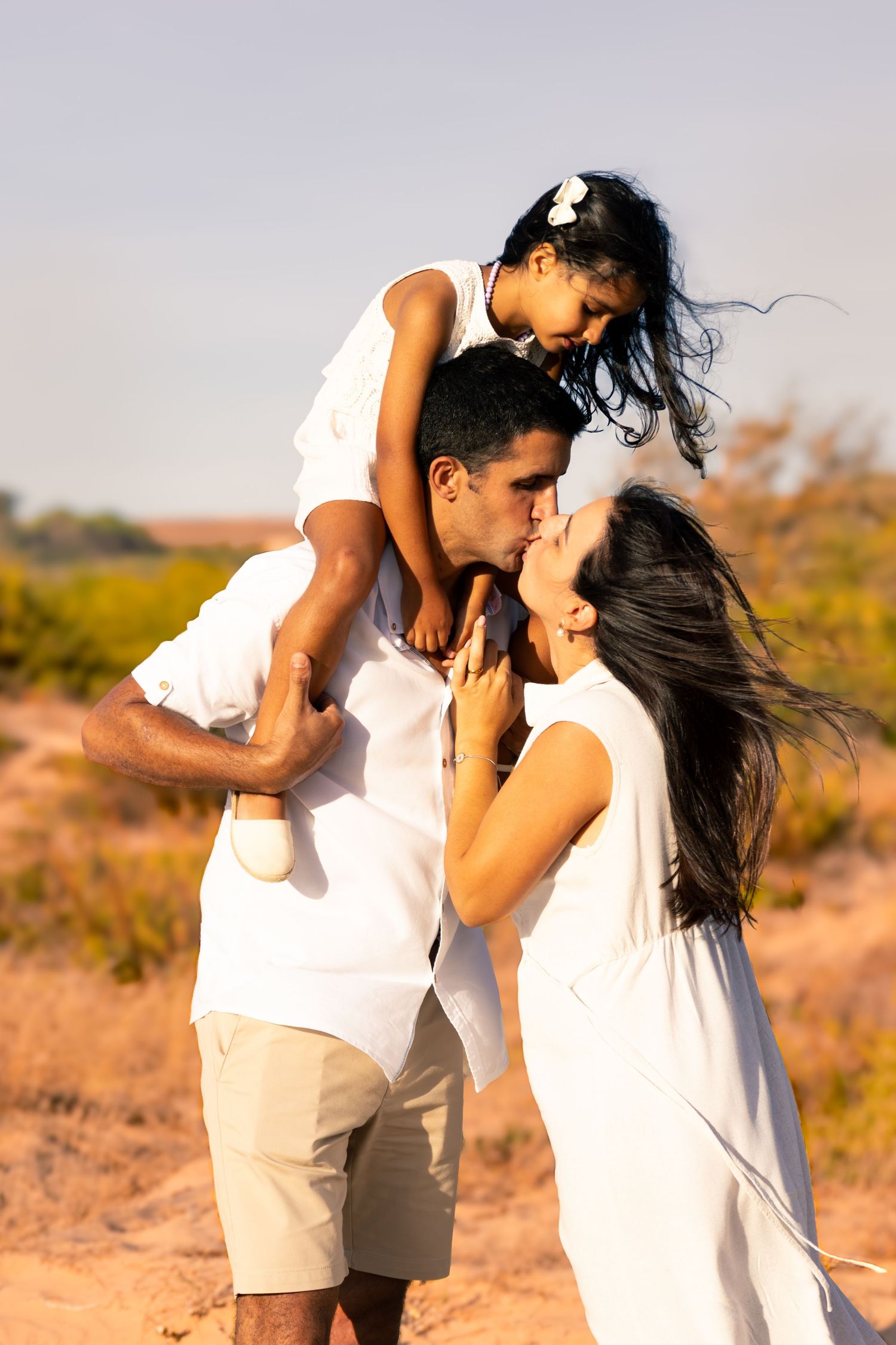 Romantic desert photoshoot with couple in white outfits at sunset.