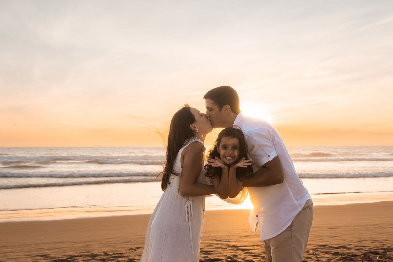 Beach engagement session with couple sharing intimate moments at sunset.