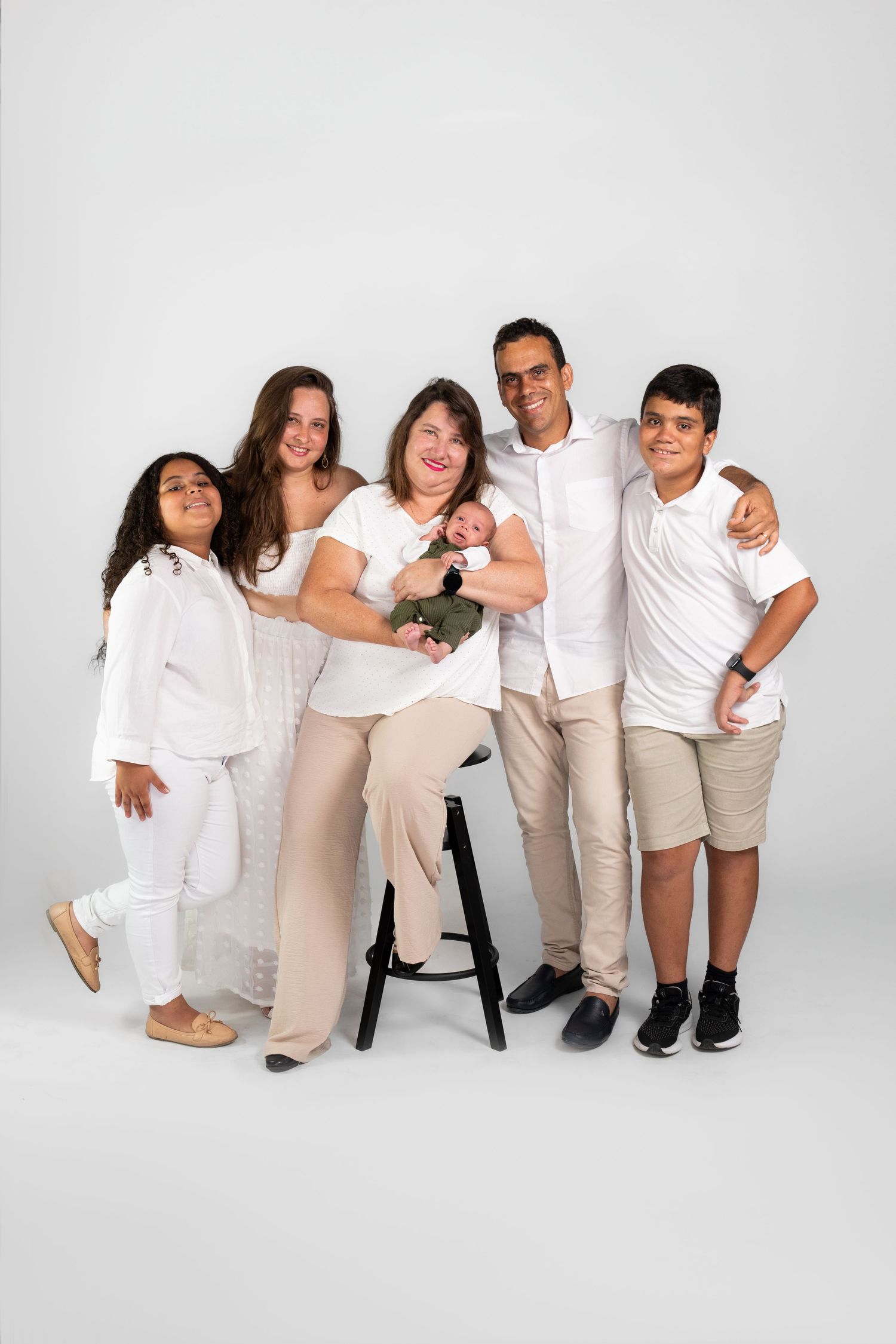 Family group photo with everyone wearing coordinated white and beige outfits.