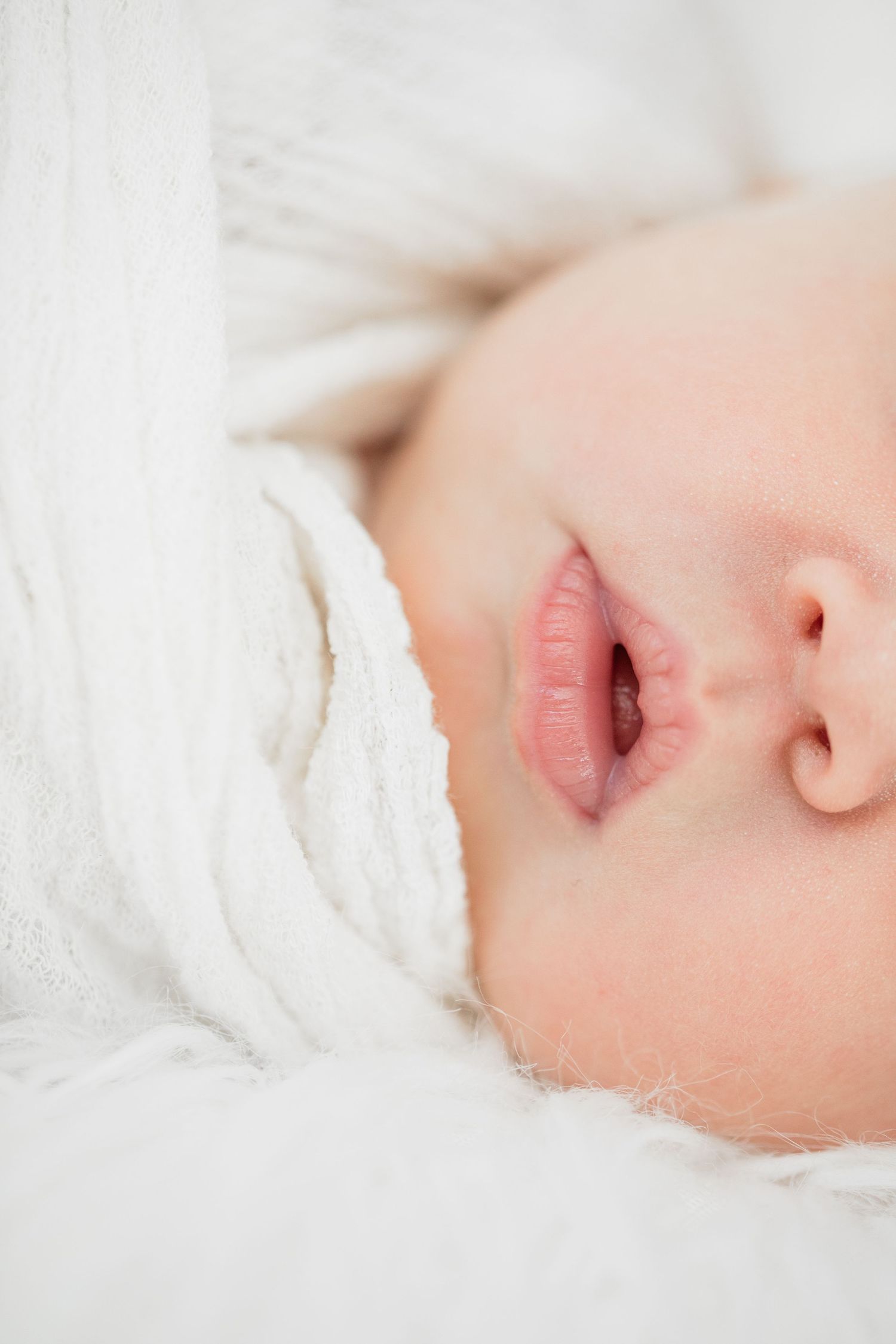 Close up shot of sleeping baby with soft white blanket in peaceful repose.