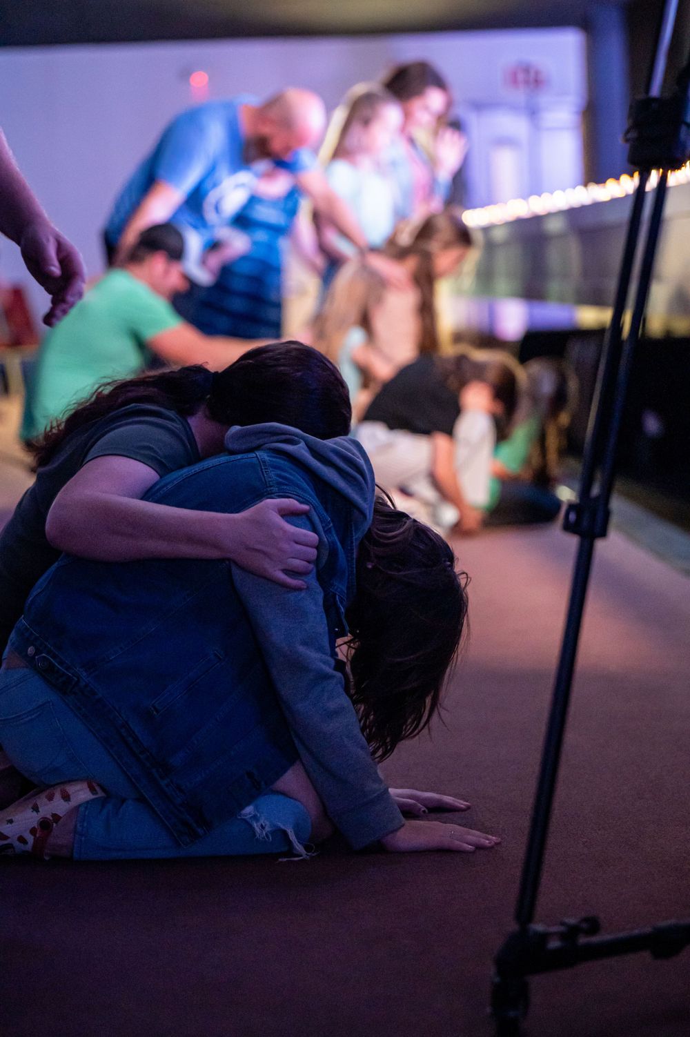 People embracing on the ground during what appears to be a spiritual or emotional gathering.