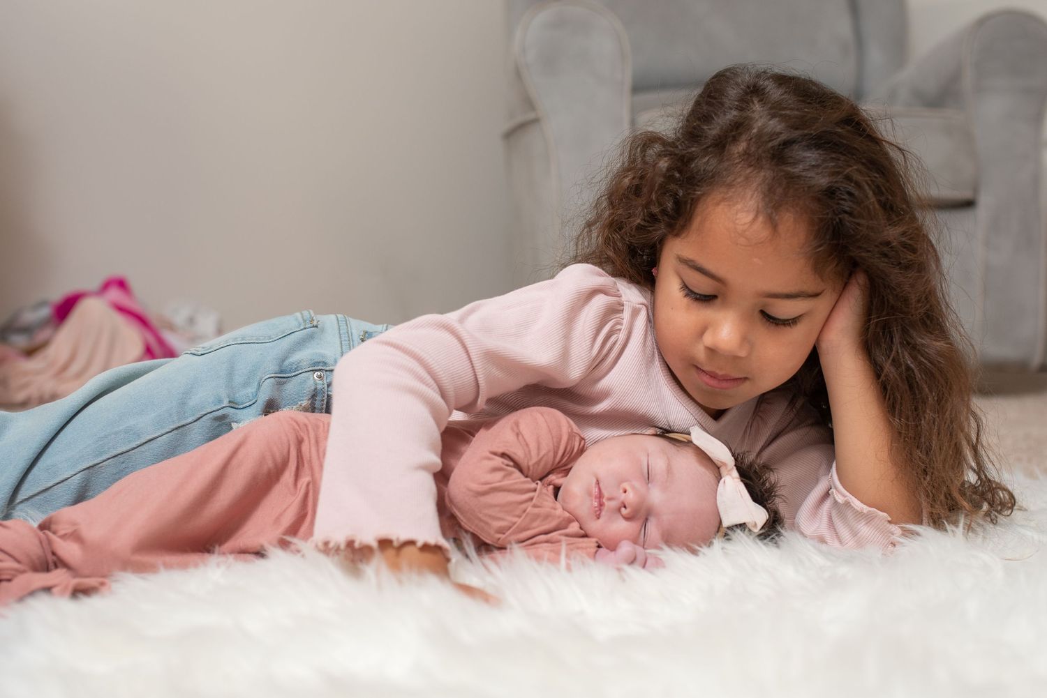 Child in pink pajamas lying peacefully on white bedding.