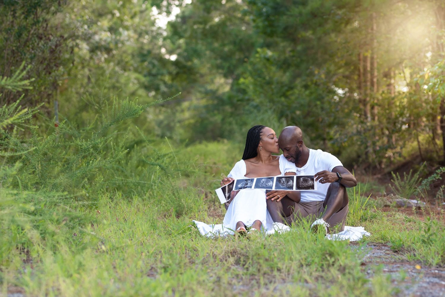 Maternity photos taken in grassy field during golden hour sunset.