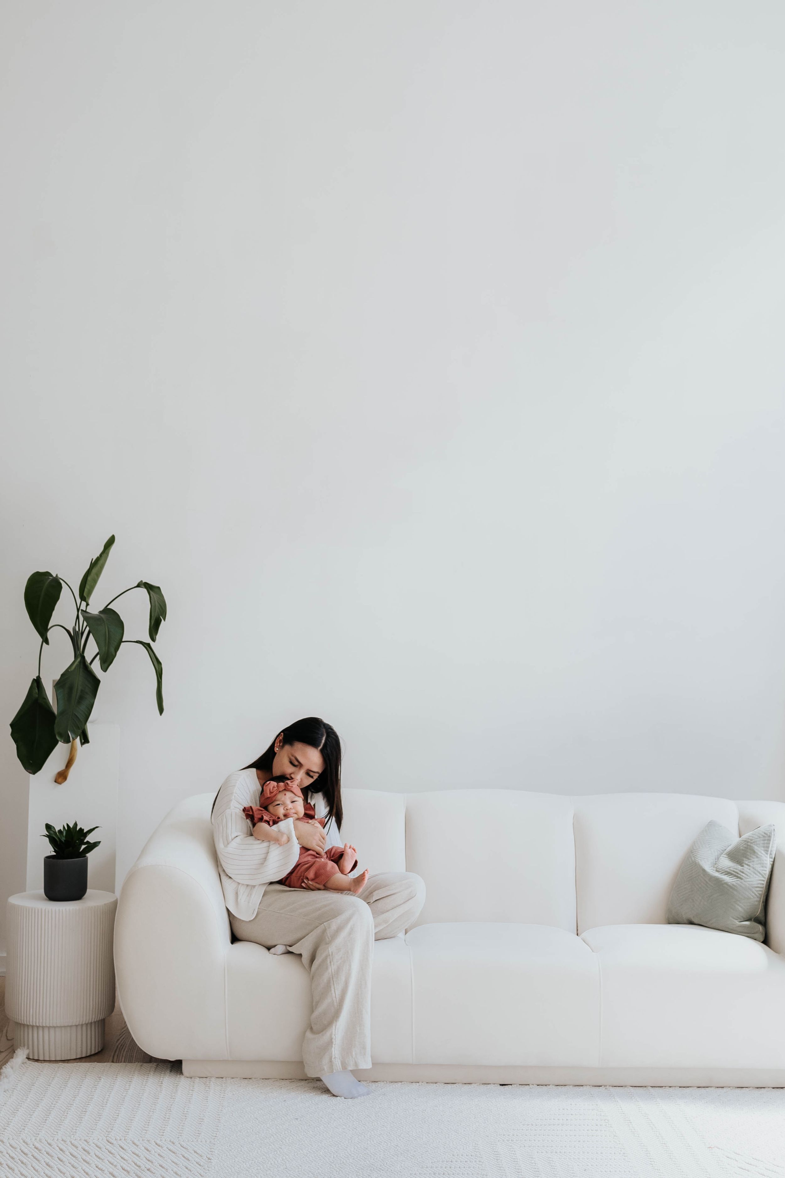 A cozy scene of relaxation on a white sofa with a houseplant in a minimalist setting.