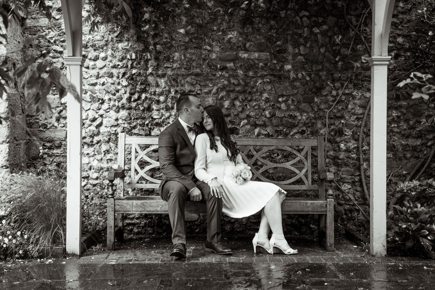 Bride and groom after wedding sitting on a bench while raining - couple intimate moment
