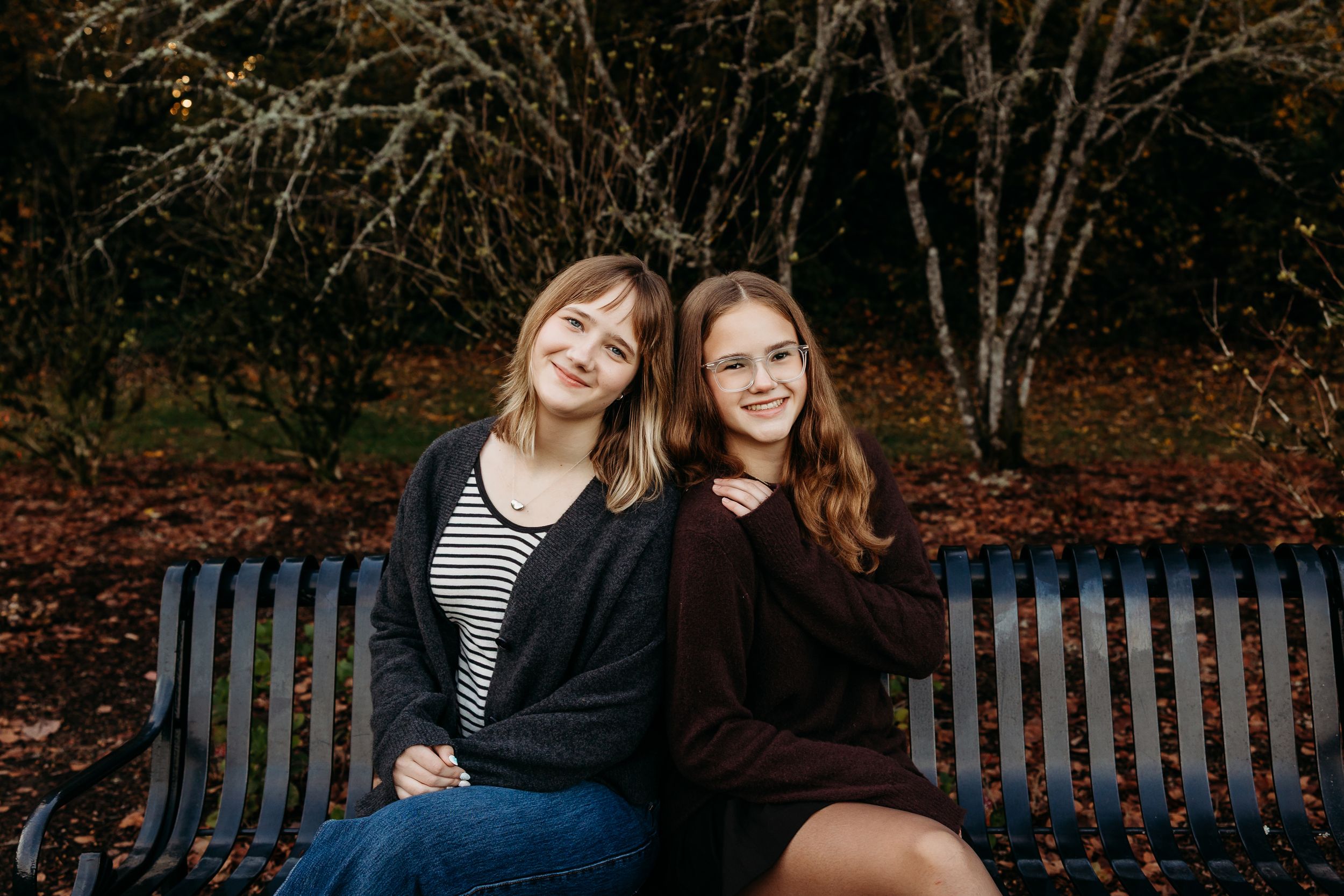 A couple shares a tender moment while sitting on a park bench during autumn.