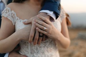 Close-up view of hands holding a coffee cup against a scenic outdoor background at sunset.