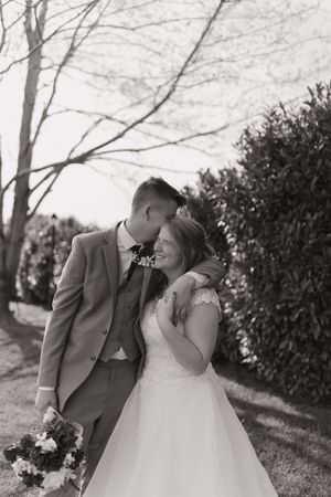 A romantic wedding photo series showing a couple in formal attire sharing intimate moments outdoors in a natural setting.