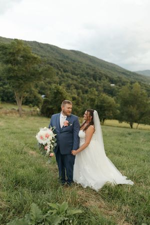 A couple shares an intimate moment together in a scenic mountain meadow during their outdoor wedding celebration.