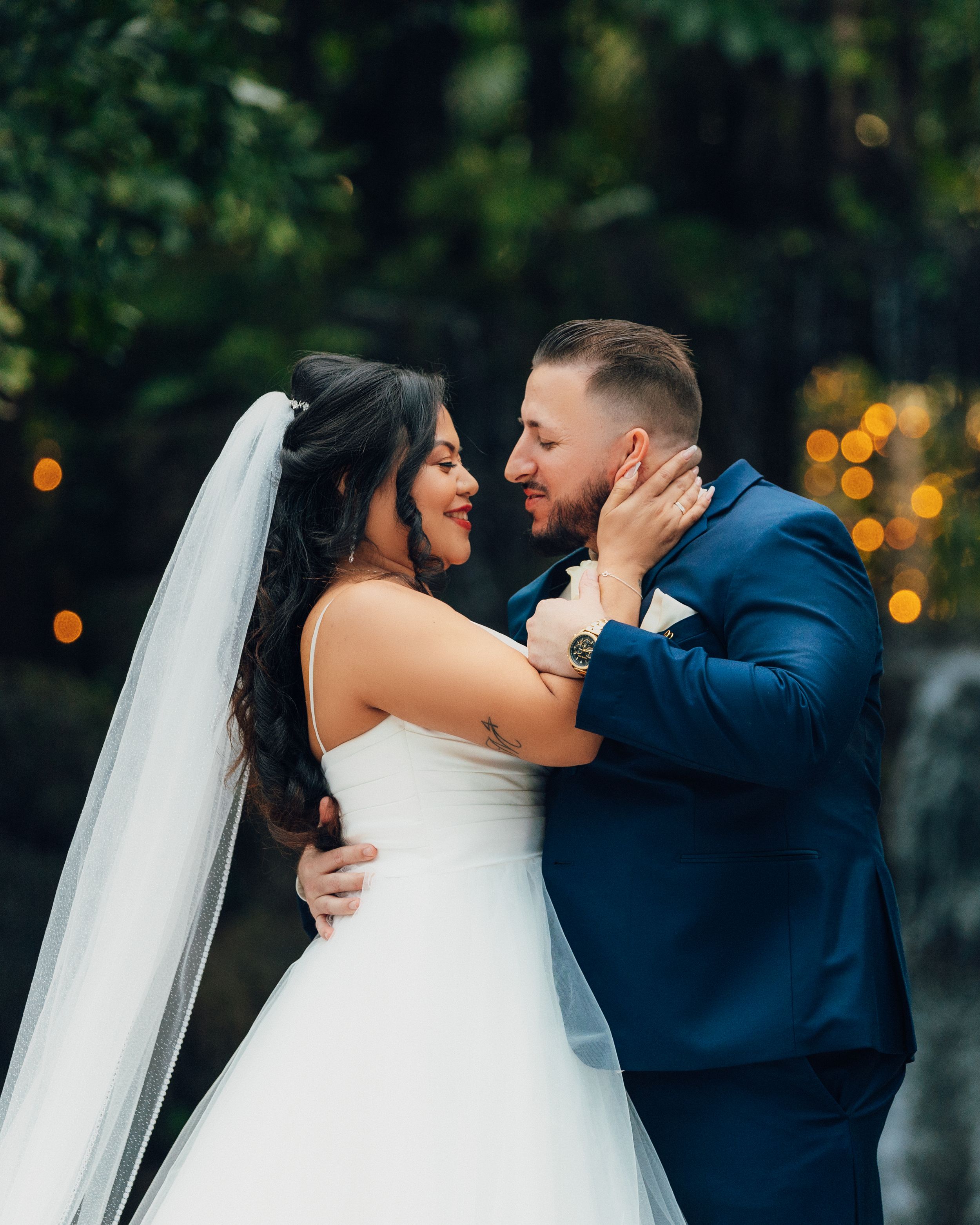 Intimate wedding portrait of couple sharing romantic moment with flowing white veil.