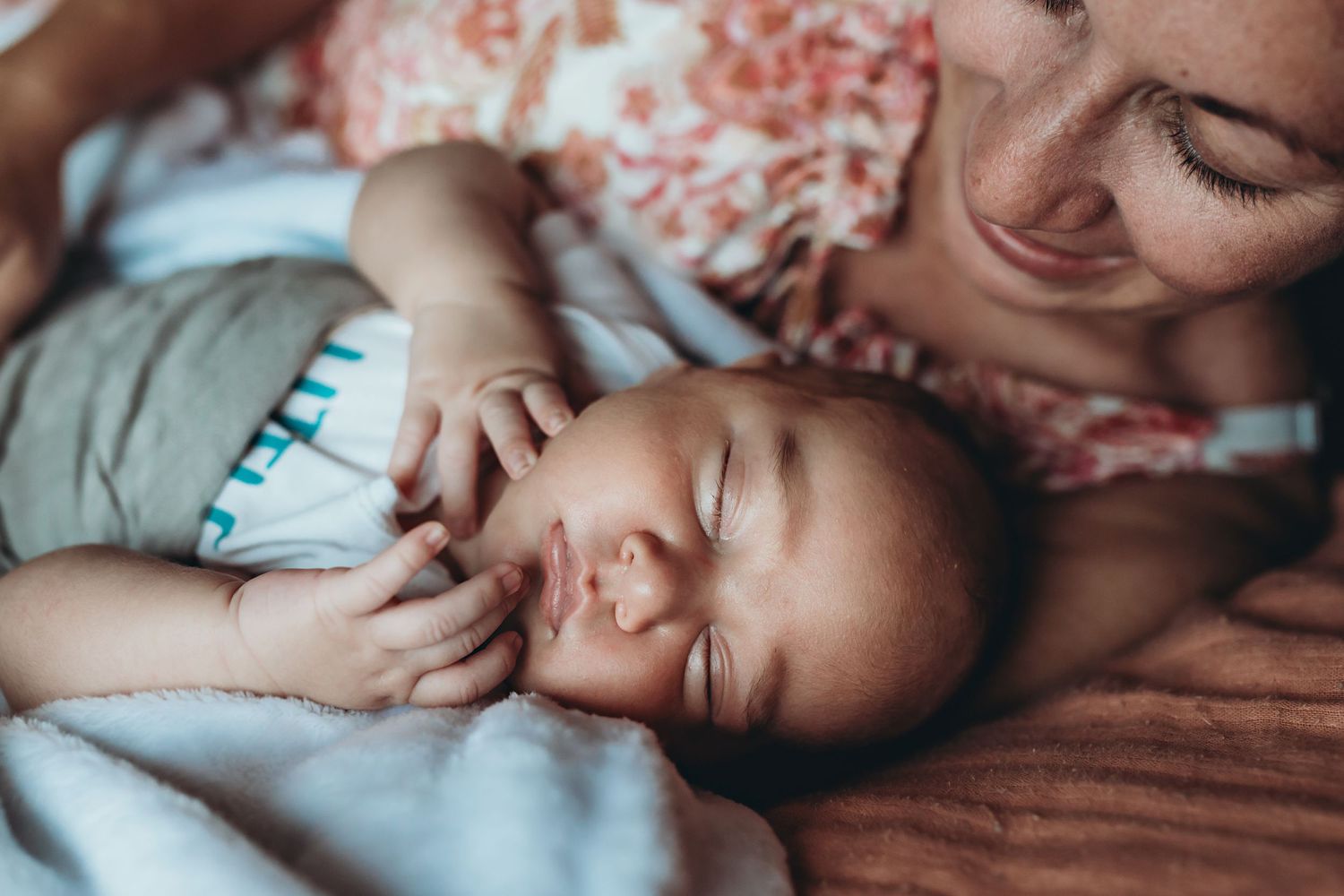 A tender moment captured of a sleeping baby in striped clothing resting close with loving care.