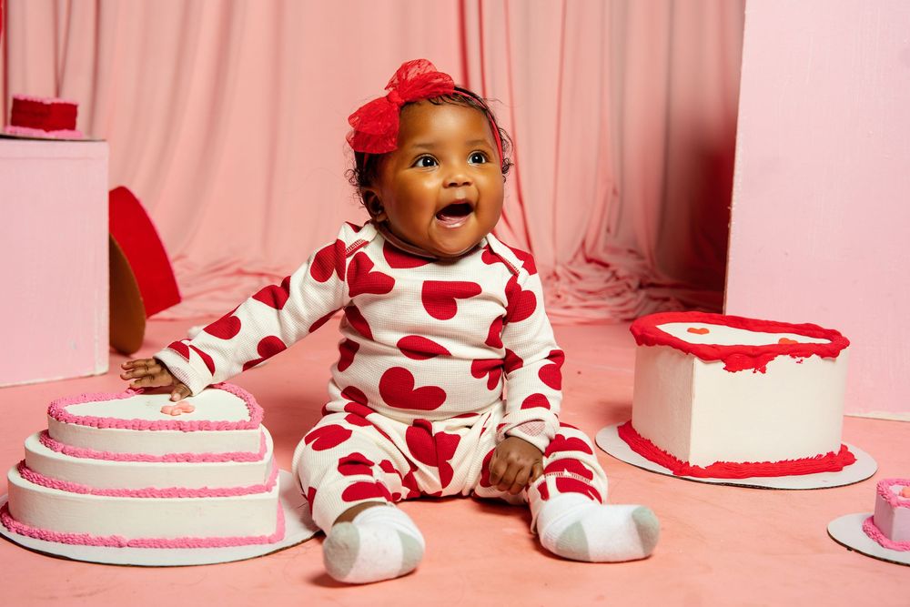 A series of birthday cakes with red and white decorations arranged in a row against a pink background.
