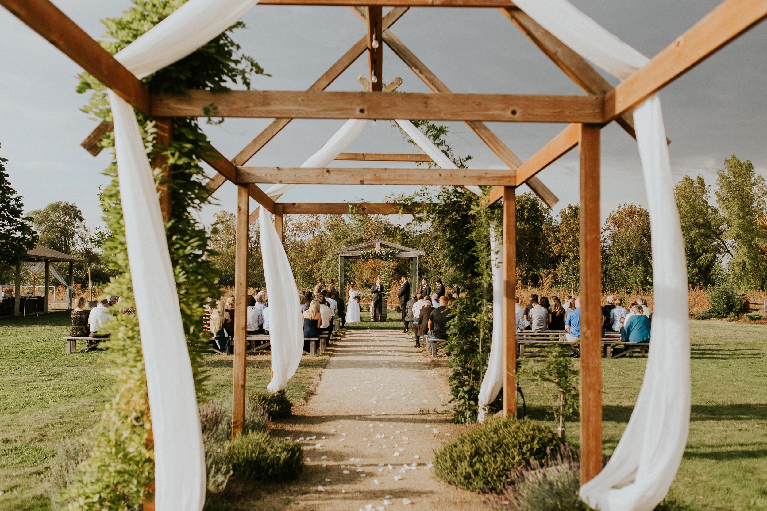 Elegant outdoor wedding venue with white draped wooden pergola and natural landscaping. Creekside Farm wedding venue. Oregon photographer.