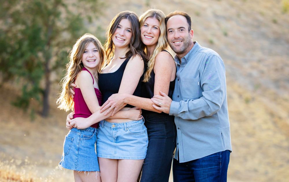 A happy group stands together for a portrait outdoors on a sunny day against a natural background.