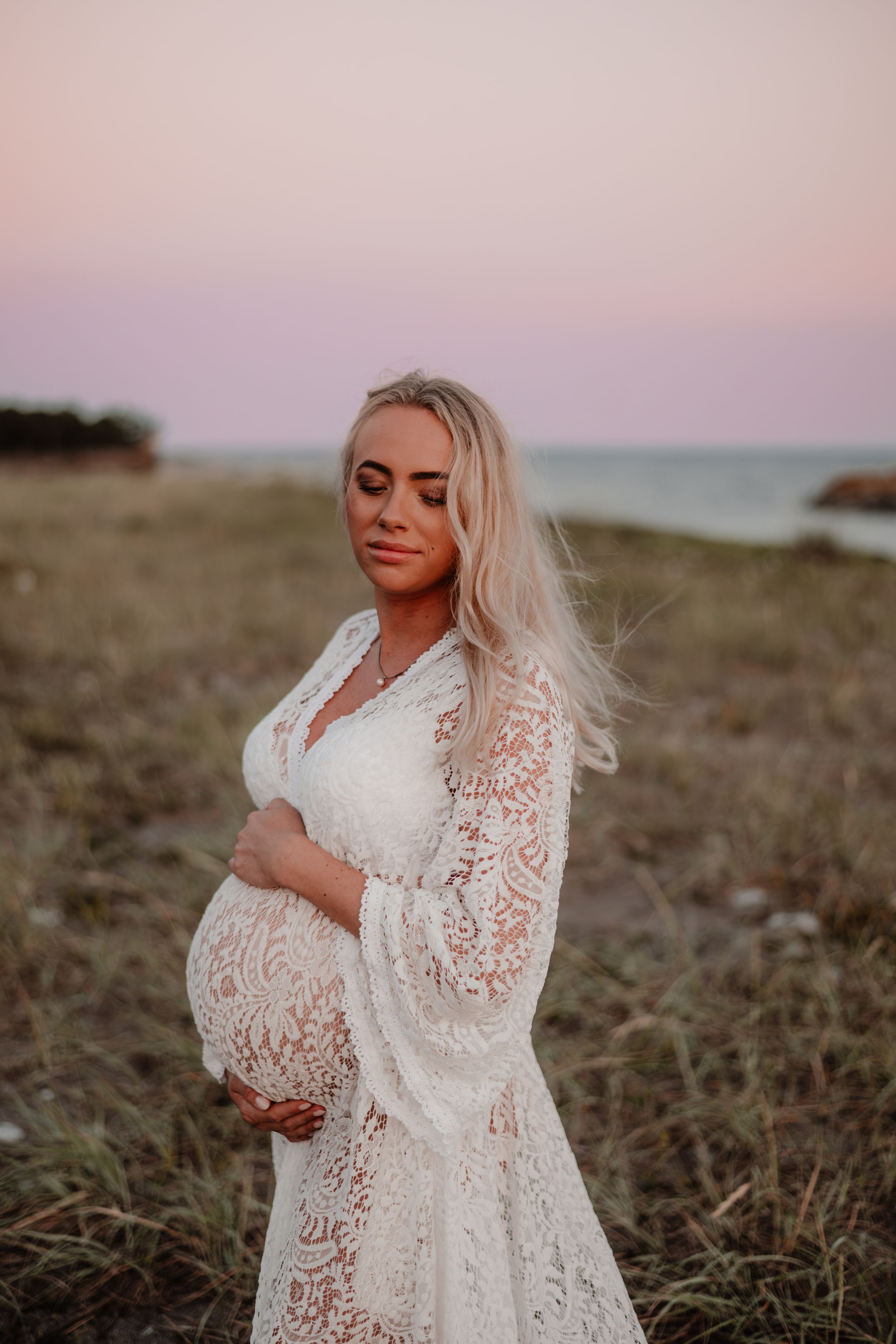 Gravid under rosa himmel i spets klänning