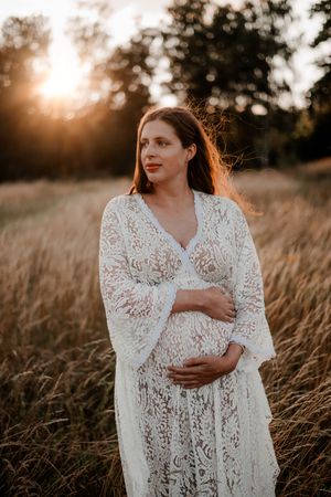 Gravid på äng med beige strån