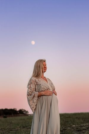 Gravid under rosa himmel med måne i bakgrunden