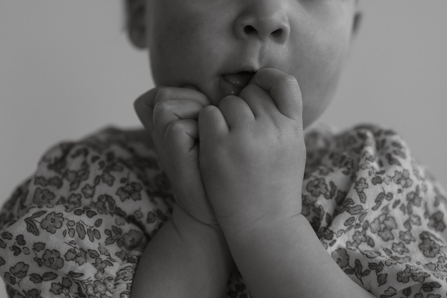 Gentle hands hold a small infant while sitting together in soft lighting.