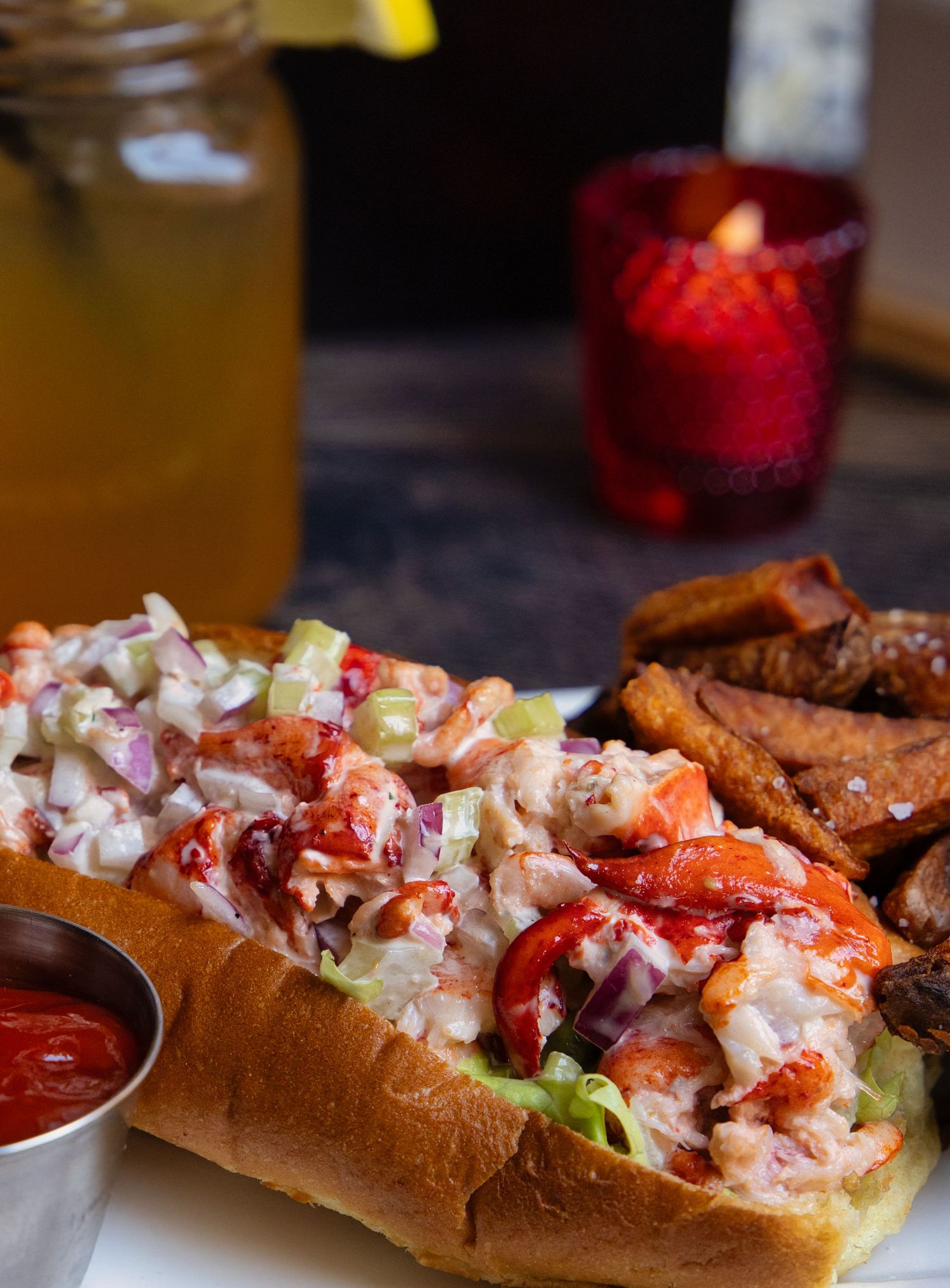 Lobster roll sandwich with fresh seafood salad and garnishes on rustic wooden surface.