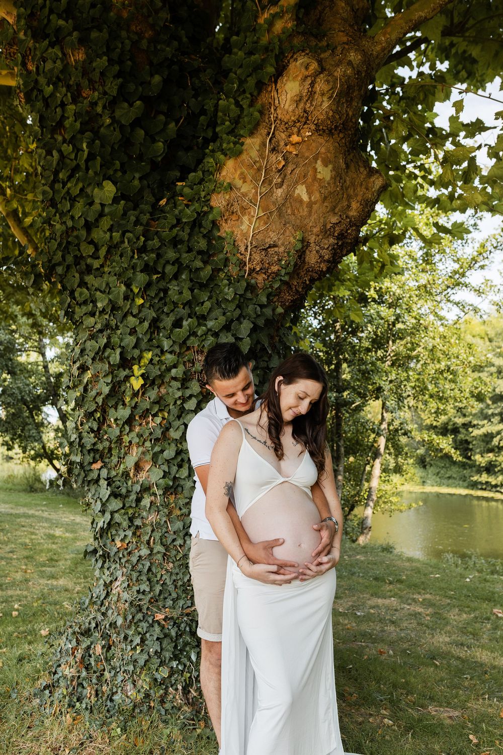 Futurs parents complices s'enlaçant lors d'une séance photo grossesse en extérieur dans la campagne niortaise, Deux-Sèvres.