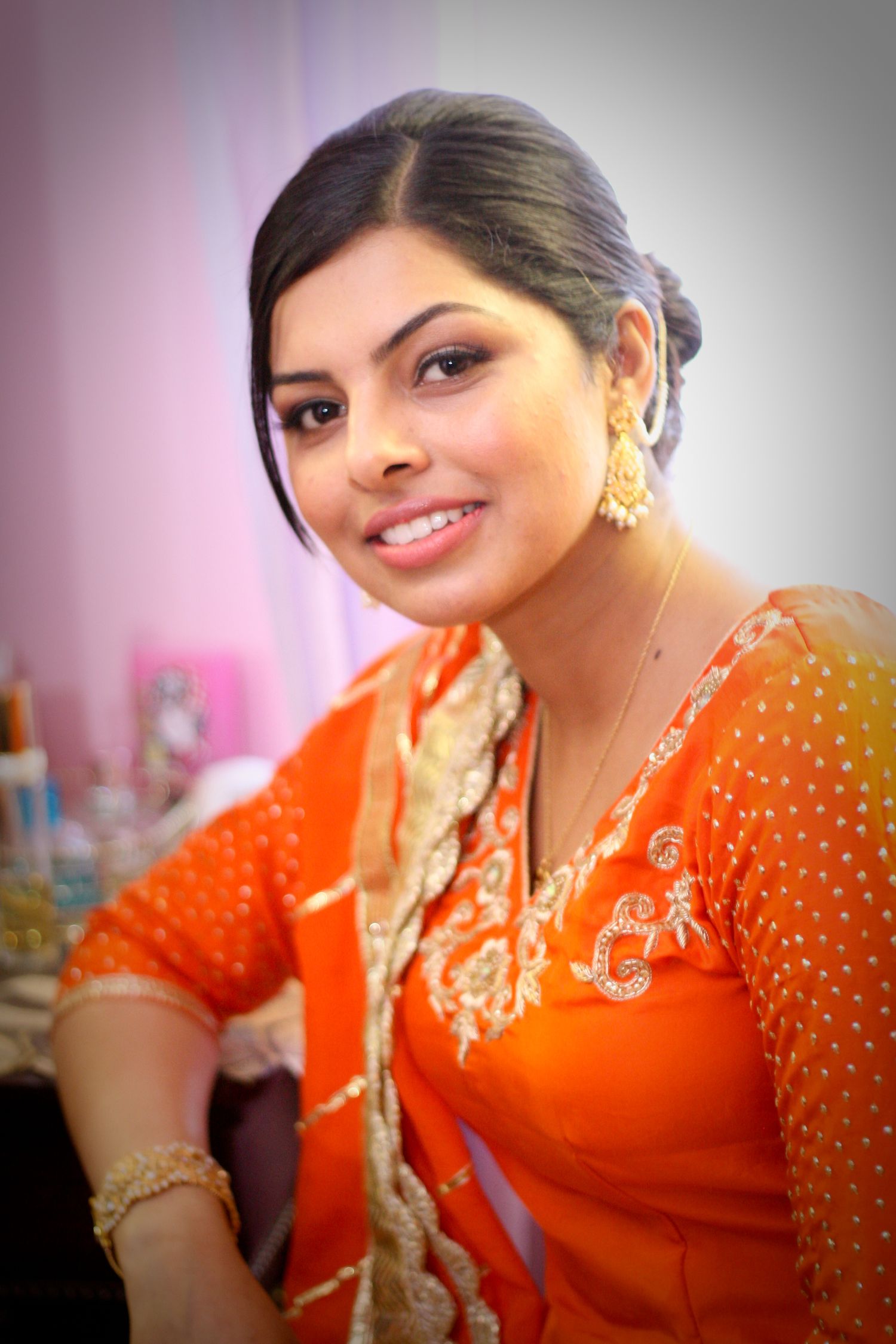 Traditional South Asian attire featuring bright orange and gold sari in portrait setting.