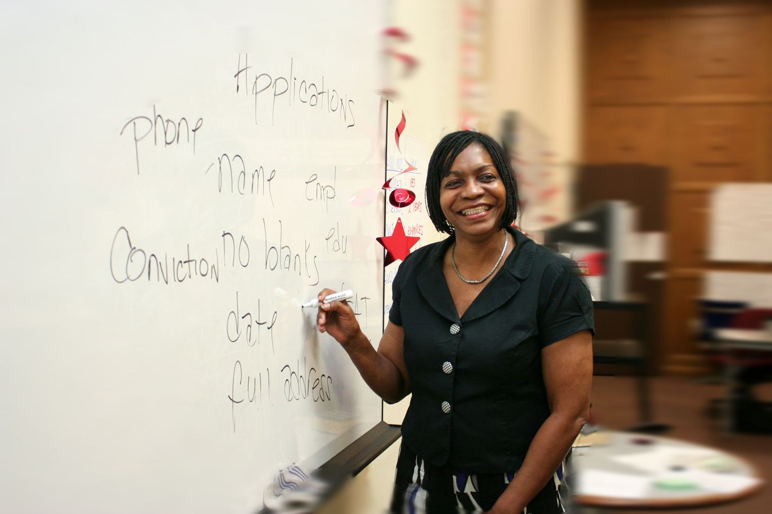 Teacher writing educational content on whiteboard in classroom setting.