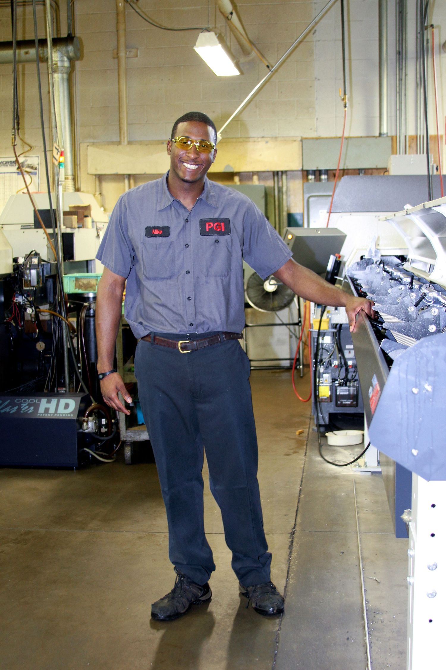 Maintenance technician in uniform standing beside industrial equipment in workshop.