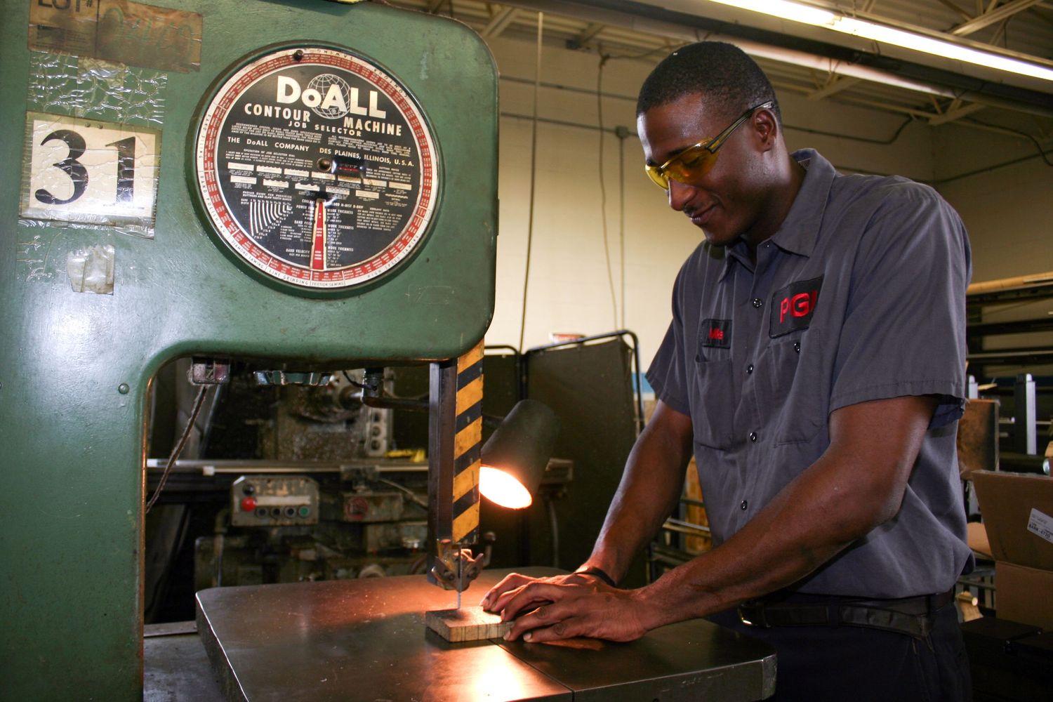 Industrial worker operating machinery in manufacturing facility with safety equipment.
