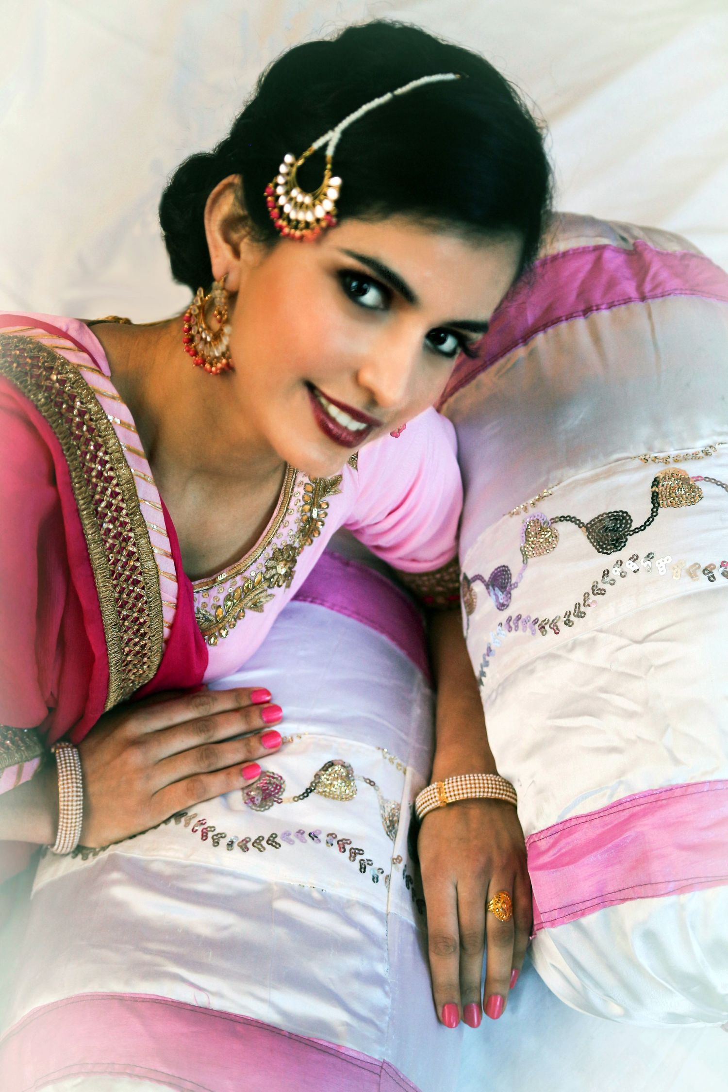 Traditional South Asian formal portrait with detailed pink and white outfit and jewelry.