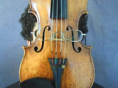 Close-up detail of an aged wooden violin showing its ornate f-holes and bridge.