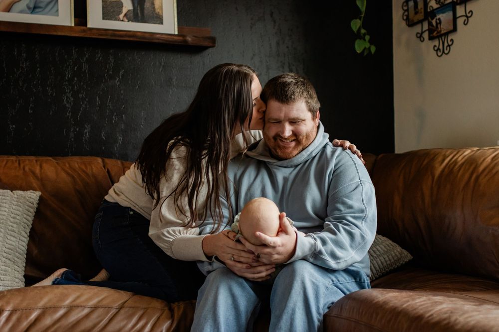 Couple sharing a joyful moment on a brown leather couch in a cozy living room.