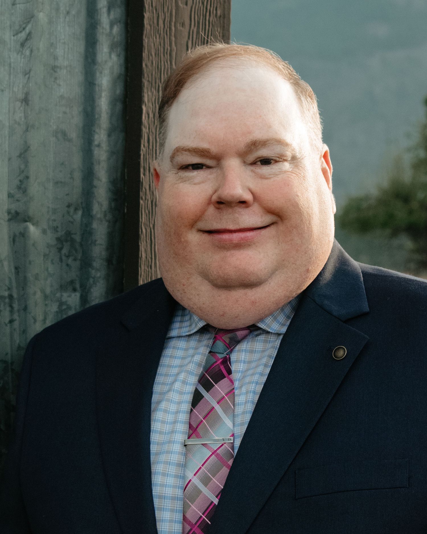 A series of headshots showing someone in a navy suit and pink striped tie against a gray background.