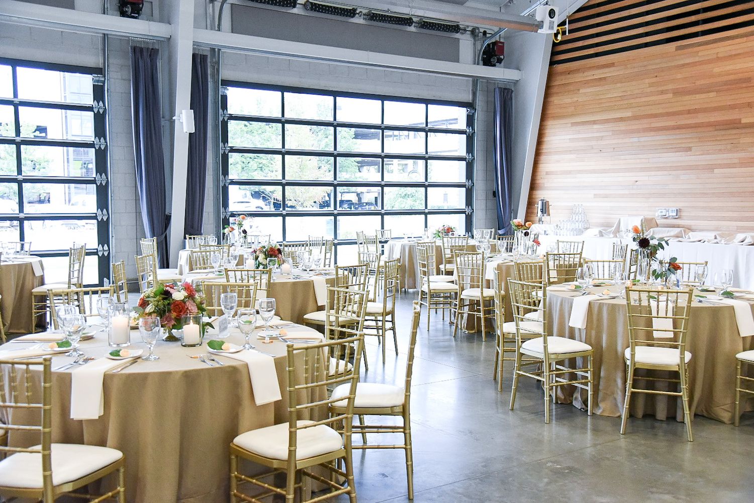 Spacious modern wedding venue with white chairs and natural lighting from large windows.